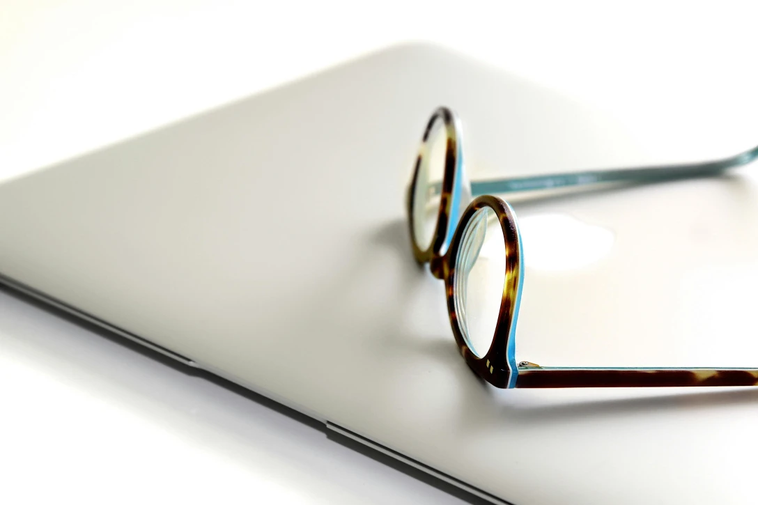 black and blue framed eyeglasses on silver laptop